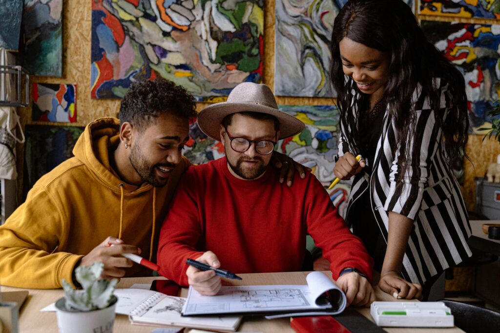 men and woman discussing project in a sketchbook and abstract paintings hanging on a wall